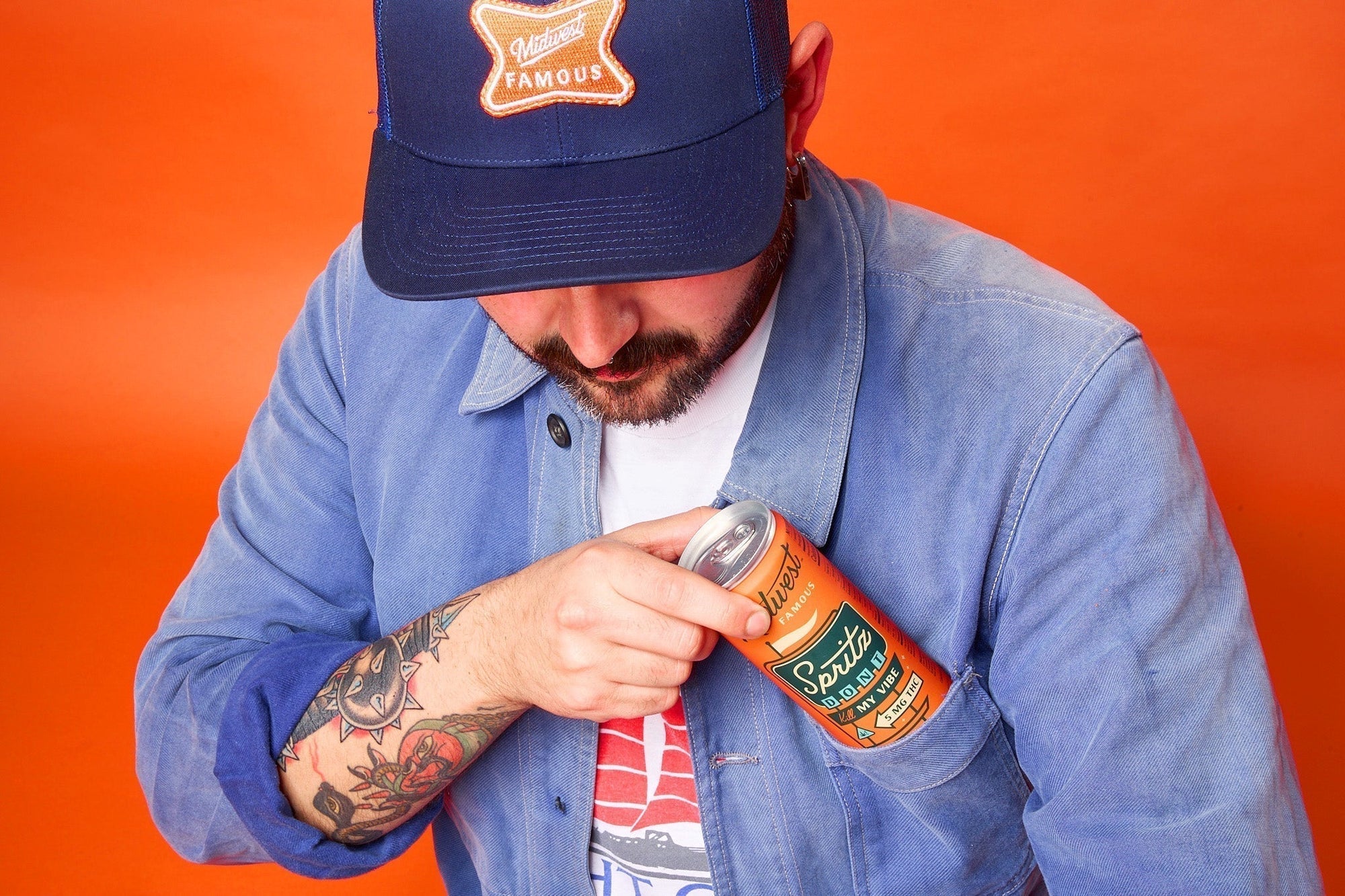 a man putting an orange can into his shirt pocket