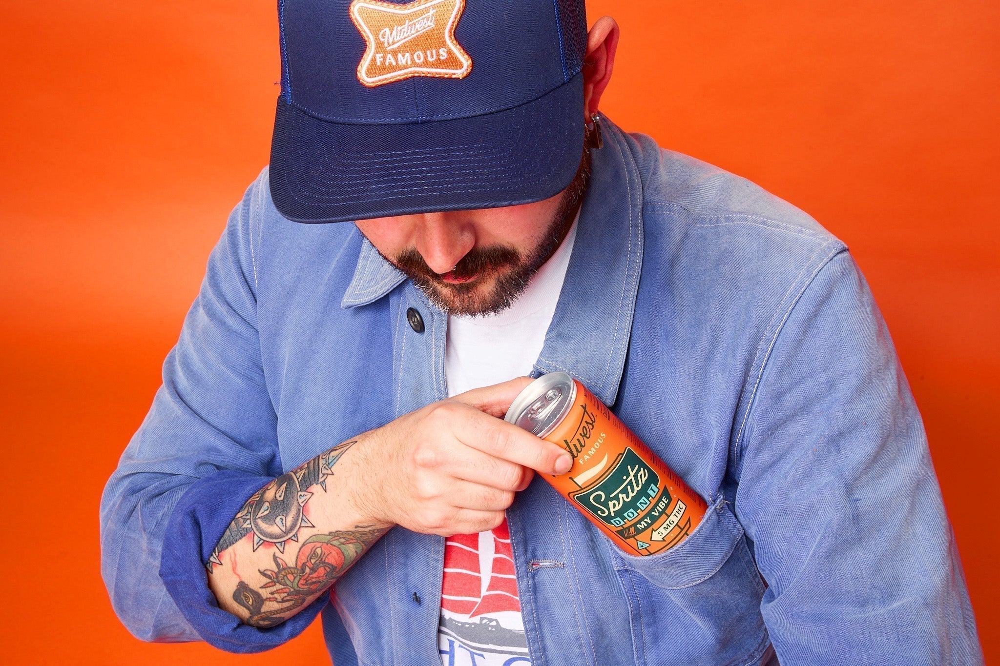 a man putting an orange can into his shirt pocket