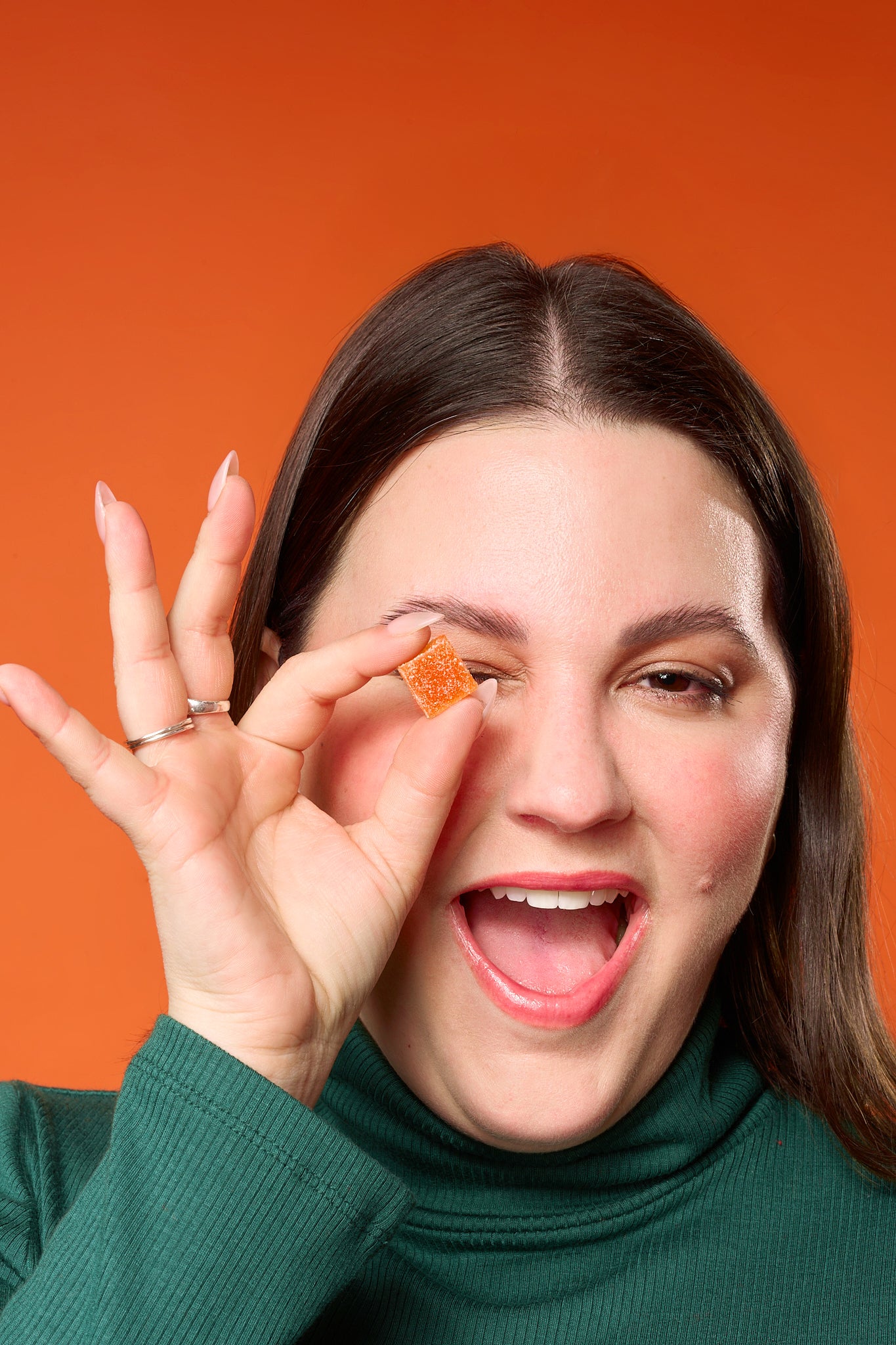 a close up of someone holding a thc gummy over their eye
