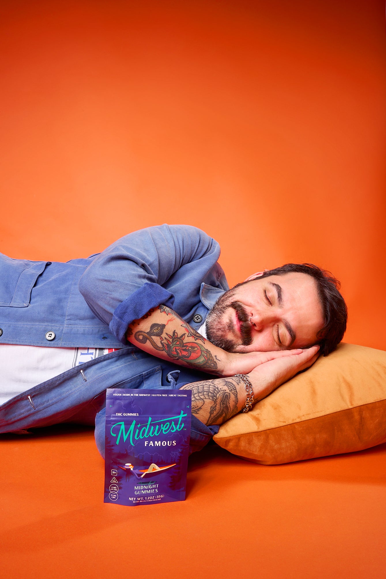 a man sleeping on an orange pillow laying next to a dark blue thc gummies bag
