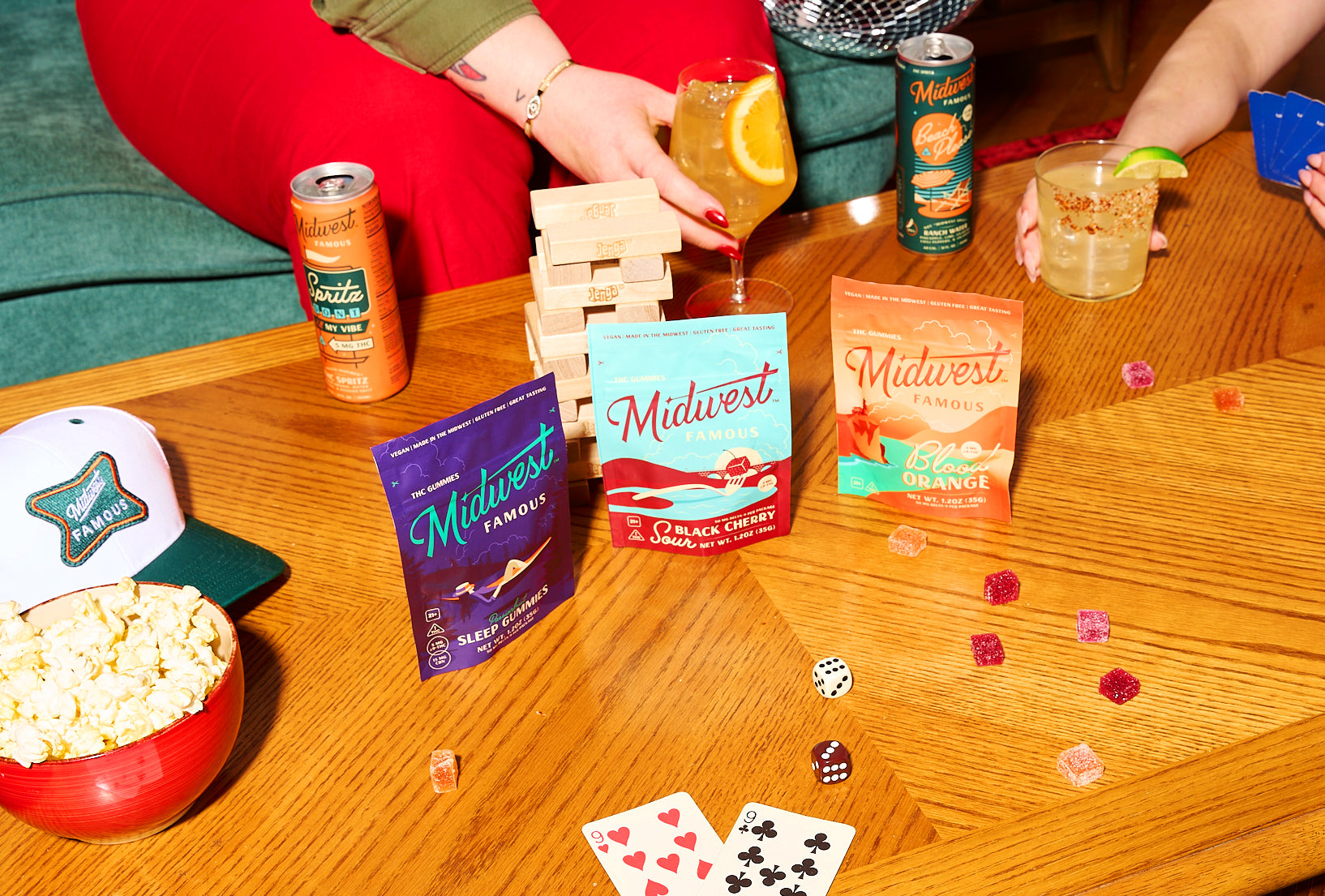 three bags of thc gummies on a table with scattered gummies, dice, and jenga blocks